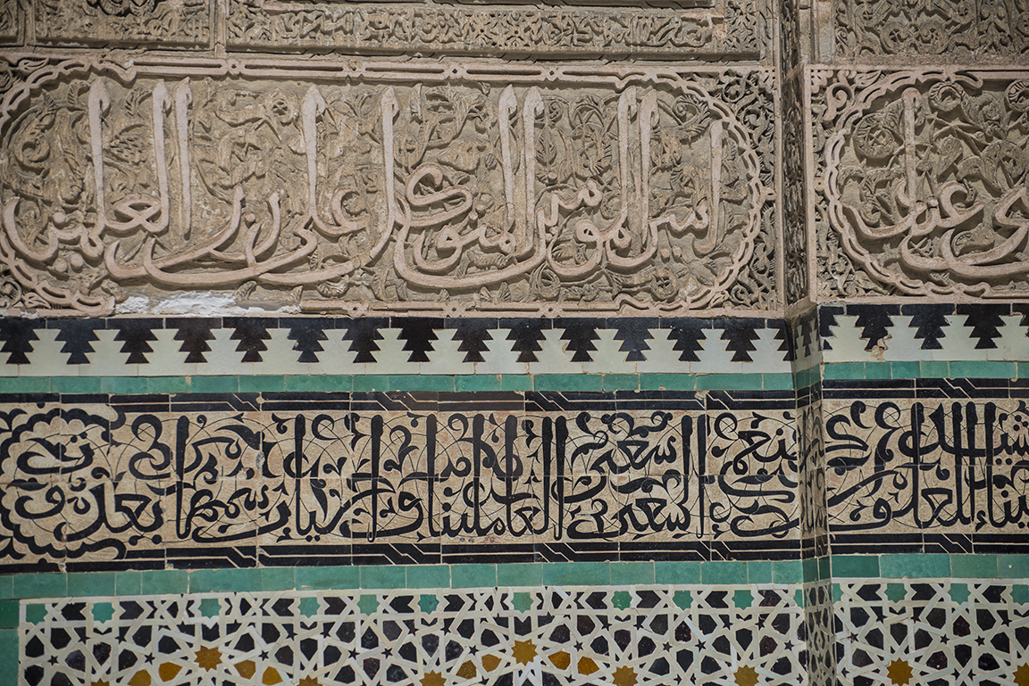 Islamic calligraphy and zellij tilework in the courtyard of the Medersa Bou Inania